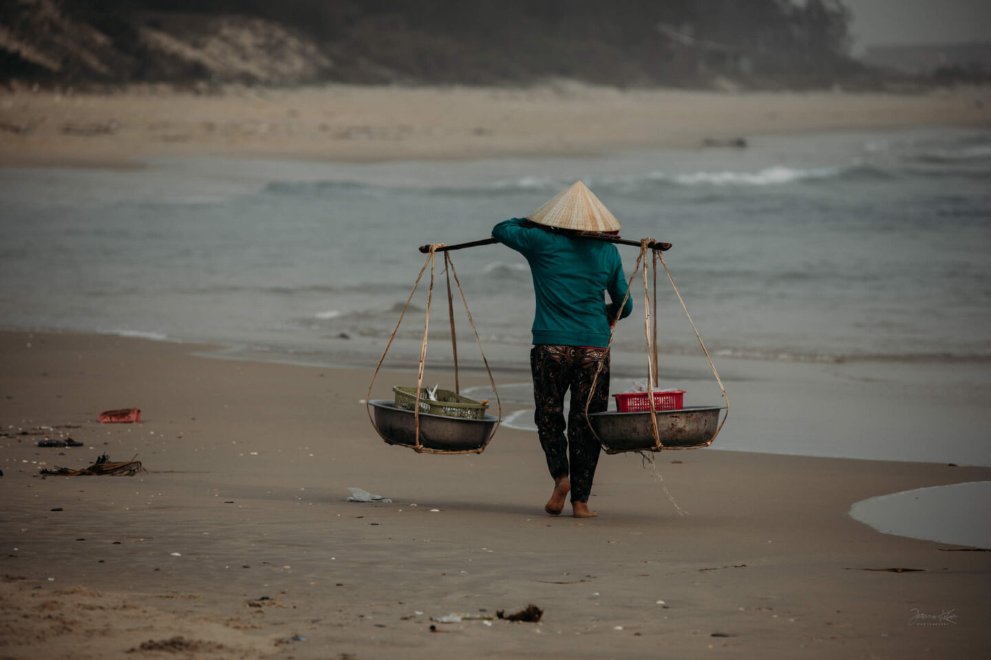A woman carries fish to a local market, Hoi An area, Central Vietnam.